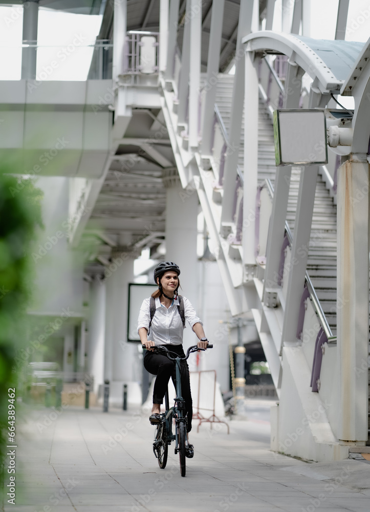 Fototapeta premium Eco friendly, businesswoman ride bicycle in urban to reduce carbon footprint. Beautiful woman environment preservation person commuting with bicycling. Cycling, alternative transport for green energy.