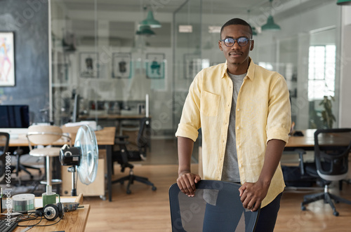 Young African businessman leaning on a chair in a modern office