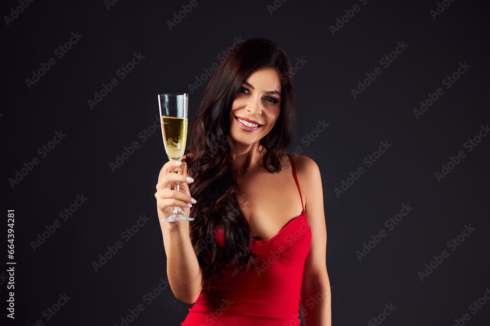 An attractive brunette woman holding a glass of champagne, smiling for the camera, dressed in a red dress. An attractive brunette woman holding a glass of champagne, smiling for the camera, dressed in a red dress.