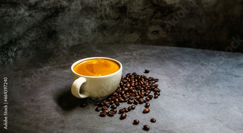 A cup coffee of espresso with coffee golden crema and coffee beans on a grey background.