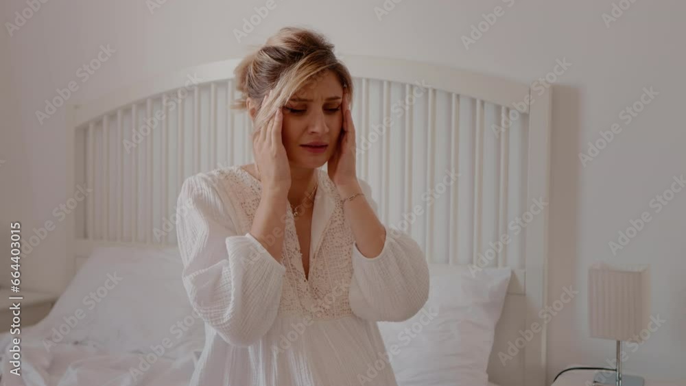 Young pregnant woman suffering for headache sitting on the bed at home close up. Awaiting mother having migraines in the morning. Young pregnant woman suffering for headache sitting on the bed at home close up. Awaiting mother having migraines in the morning.