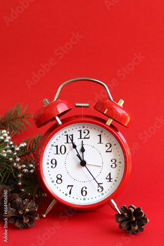 The red alarm clock is on a red background with Christmas decorations.