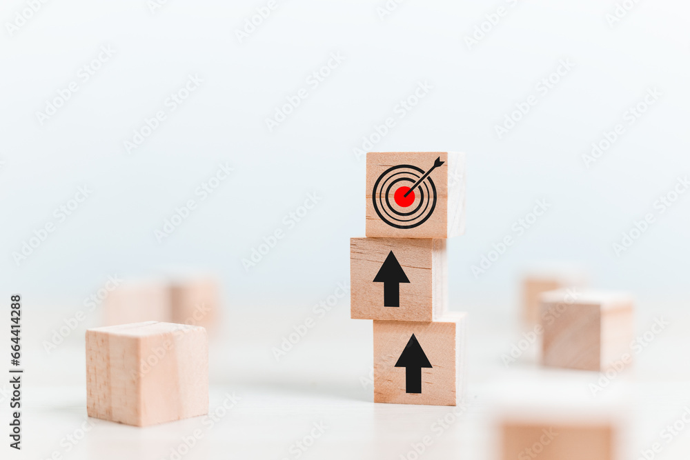 Obraz premium Concept of step to goal. wooden cube block arrows up and goal on table. Target business growth success. Vision teamwork corporate leading to progress.