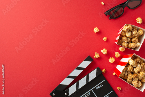 Cinema premiere setup. Top-down view of a filmmaker\'s clapper, 3D eyewear, delectable striped popcorn boxes on a red surface with space for your text or promo