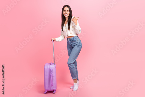 Full length photo of cheerful excited woman dressed white shirt going vacation thumb empty space isolated pink color background