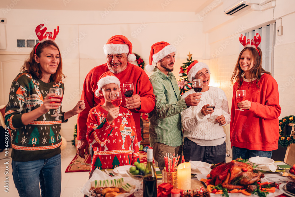 Obraz premium Group of happy family smiling happy celebrating christmas toasting with wine. Family member enjoy home made turkry grill dining togather at home. Christmas and New Year interior concept.