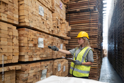 Warehouse staff verify wooded pallets items using handheld device, ensuring precise shipment.