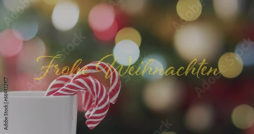 Animation of frohe weihnachten text over candy canes in mug over spot lishts background photo