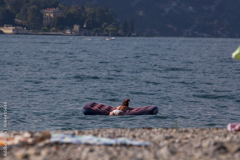 Fototapeta premium woman sunbathing and relaxing on a floating mat