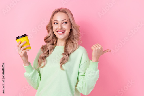 Portrait of lovely person hold coffee cup look indicate thumb finger empty space ad isolated on pink color background