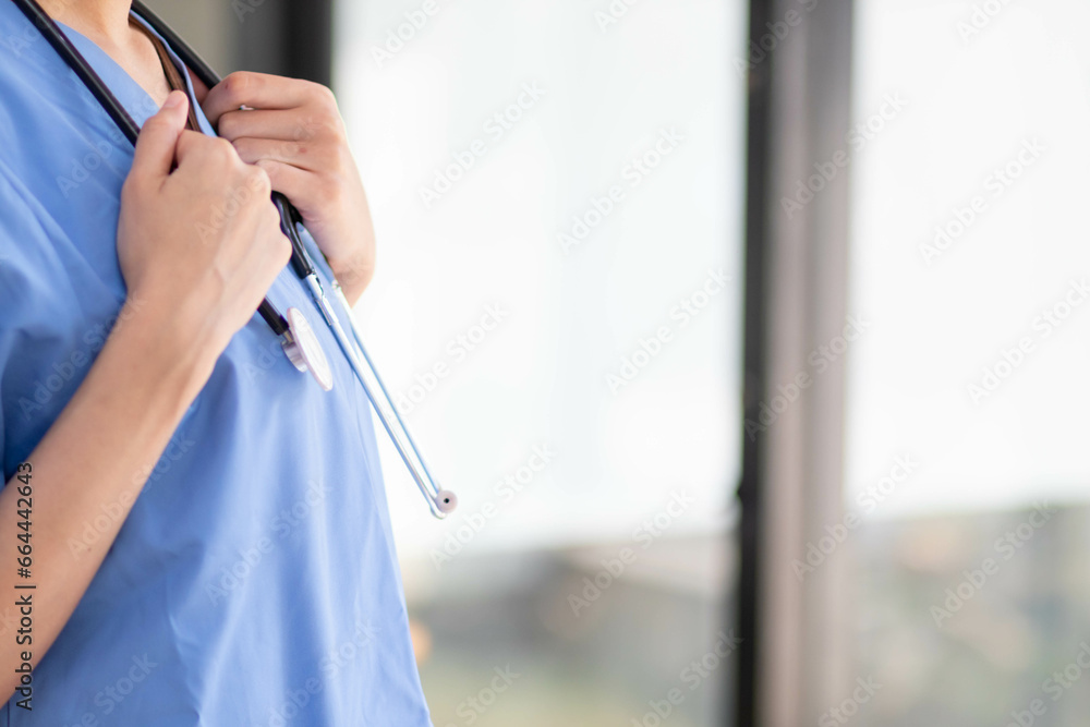 Female doctor in uniform holding a stethoscope waiting to examine a patient. A female doctor holds a stethoscope to prepare for treating patients in the hospital. Copy Space for inserting medical text