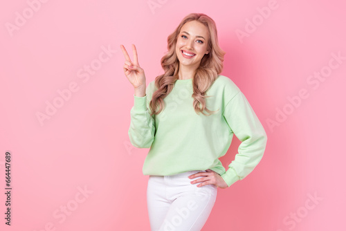 Photo of positive gorgeous person toothy smile hand fingers demonstrate v-sign isolated on pink color background © deagreez
