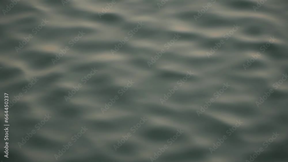 Detail and blur of the water surface which is wavy due to gusts of wind. close up and slow motion of wavy water with the reflection of yellowish sunlight in the afternoon Detail and blur of the water surface which is wavy due to gusts of wind. close up and slow motion of wavy water with the reflection of yellowish sunlight in the afternoon