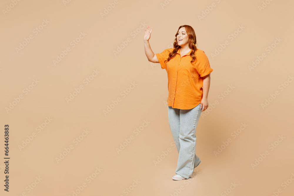 Full body side profile view young ginger chubby overweight woman wear orange shirt casual clothes walk go waving hand isolated on plain pastel light beige background studio portrait Lifestyle concept Full body side profile view young ginger chubby overweight woman wear orange shirt casual clothes walk go waving hand isolated on plain pastel light beige background studio portrait Lifestyle concept