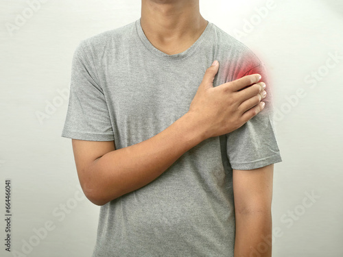 Man holding pressing his shoulder, pain ache from impingement syndrome photo