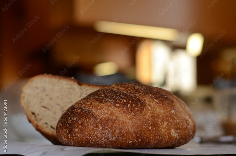 Freshly baked pretty loaf of homemade delicious sourdough bread sliced open on table/counter 