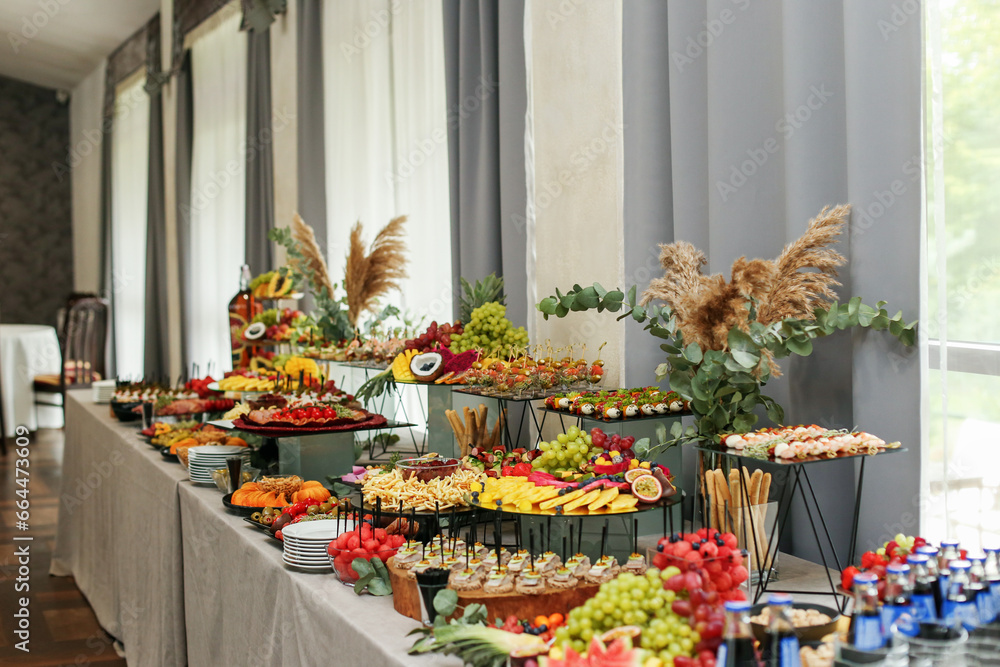 Obraz premium catering buffet table with snacks and appetizers. Set of varios fruits and berries. Decorative vase