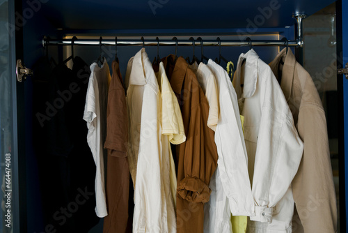 Close-up of clothes hanging on black hangers hanging in the dressing room. The concept of storing clothes in a closet and wardrobe