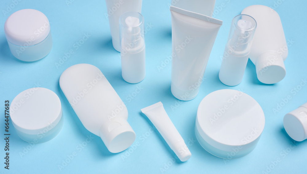 White plastic tubes, jars, and containers for cosmetic products on a blue background, advertising and branding of products White plastic tubes, jars, and containers for cosmetic products on a blue background, advertising and branding of products