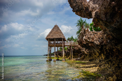  Wooden pavilion with palm leaves roof against turquoise water background, Zanzibar photo
