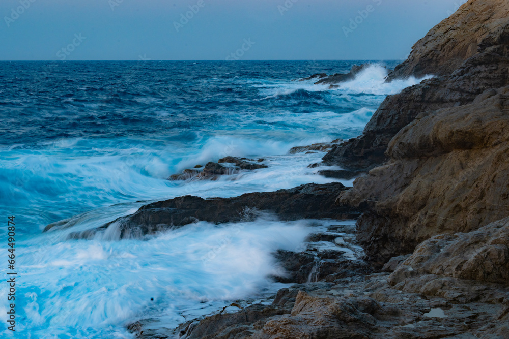 Obraz premium Long exposure photography of waves in motion hitting the rocks of the Ikarian coast