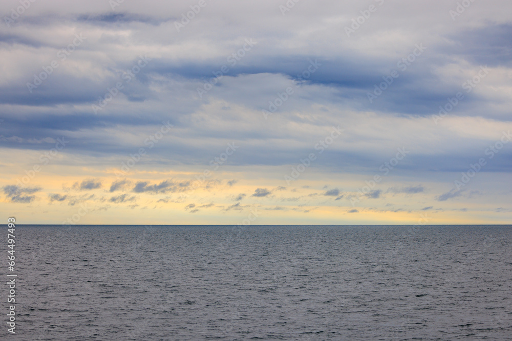 Fototapeta premium Distant horizon between cloud layer and calm seas at sunrise