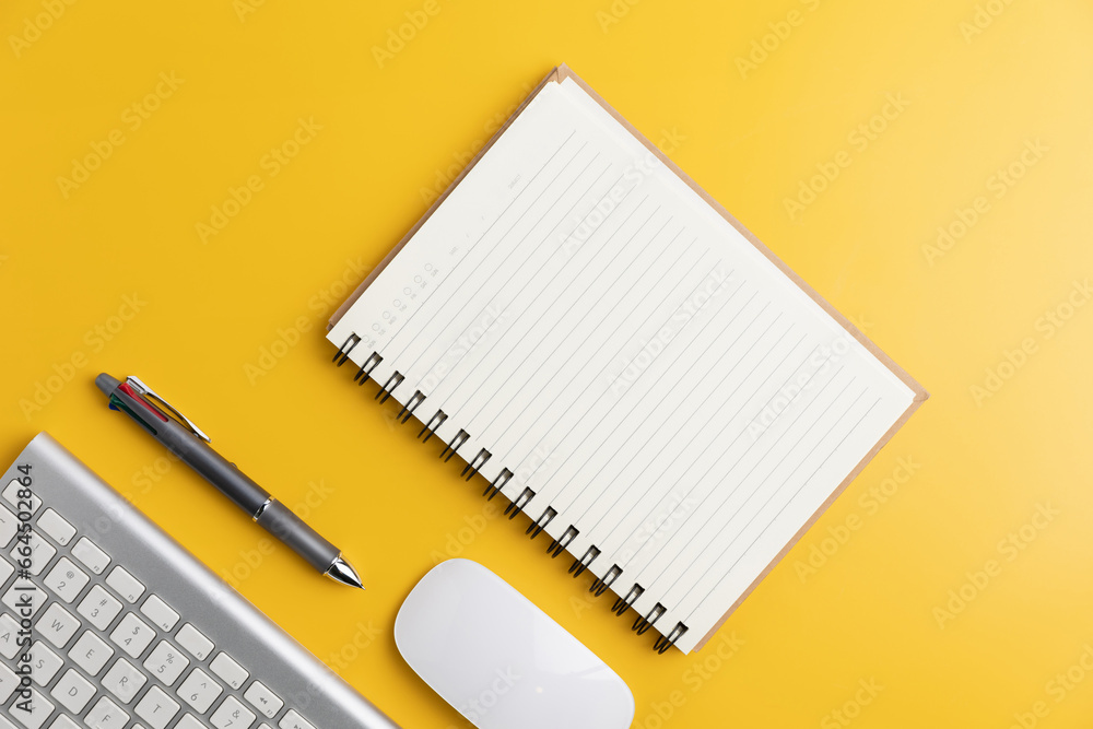 The home office with a pen, and notebook with a mouse on a yellow table with copy space. Top view, flat lay minimal yellow desk concept. Workspace desk with keyboard on yellow background. The home office with a pen, and notebook with a mouse on a yellow table with copy space. Top view, flat lay minimal yellow desk concept. Workspace desk with keyboard on yellow background.