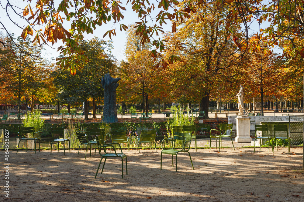 Green chairs in the autumn Tuileries Garden against a background of yellow trees, Paris, France. Beautiful view of the Tuileries Gardens in autumn