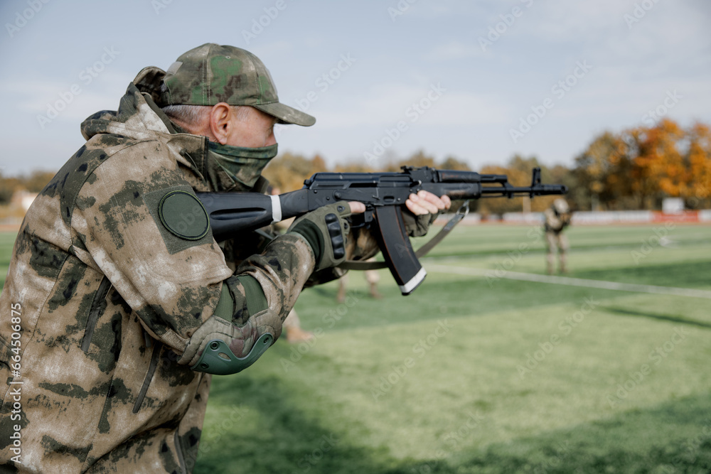 Fototapeta premium Soldiers in formation. Soldiers with a machine gun in military uniform. Special forces with weapons take part in a military maneuver. War, army, equipment and the concept of people. Camouflage. Traini
