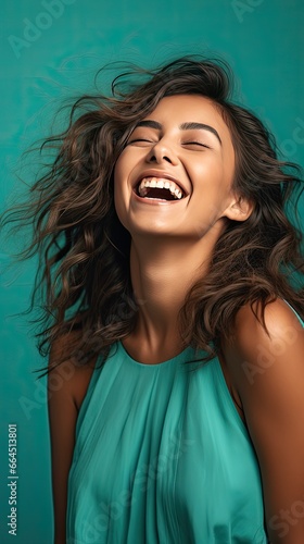 Model chuckling against a refreshing teal background, evoking a carefree and lively spirit. Vertical orientation.   © Dannchez
