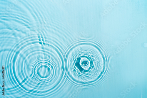 Patterns from Circles from drops on clear water Transparent blue water surface with ripples. Cosmetic moisturizing essence