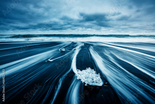 Pieces of the iceberg sparkle on the black sand.