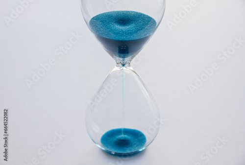 Hourglass containing blue sand isolated on white background