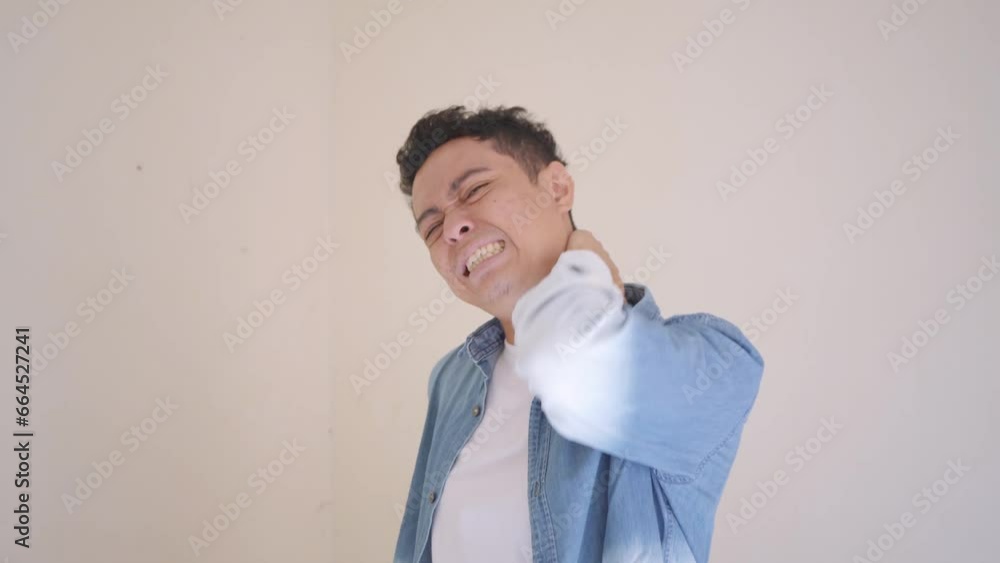 Young Indonesian man with denim style feel painful and uncomfortable. The footage is suitable to use for man expression and lifestyle content media. Young Indonesian man with denim style feel painful and uncomfortable. The footage is suitable to use for man expression and lifestyle content media.