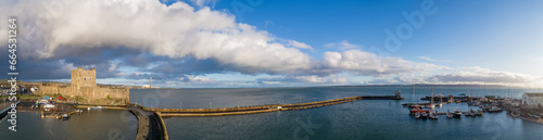 Carrickfergus near Belfast, Northern Ireland, UK. Wide aerial panorama of medieval Norman Castle, marina with yachts, boat ramp, breakwater and Belfast Lough. Winter, stormy clouds, sunset light © kilhan