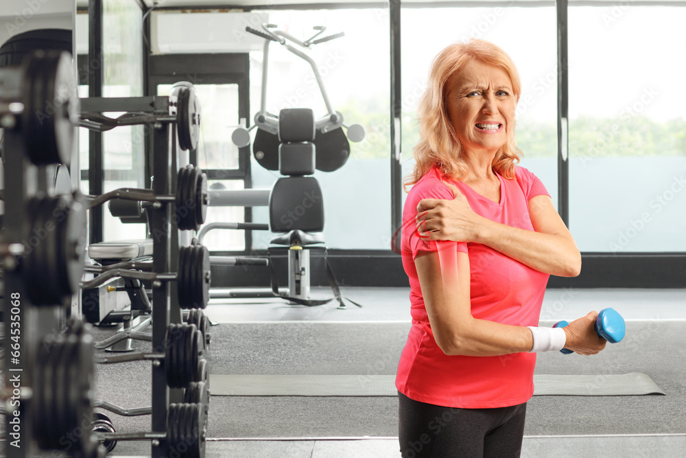 Fototapeta premium Woman with injured shoulder holding a dumbbell