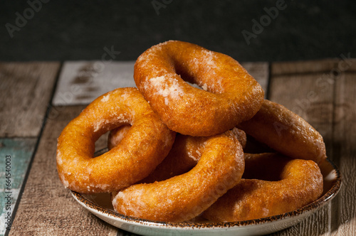 Appetizing donuts sprinkled with powdered sugar on a plate close-up