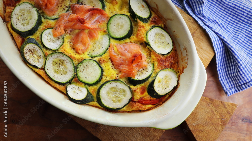 Zucchini gratin with salmon and parmesan on a wooden background. Summer pie with zucchini Zucchini gratin with salmon and parmesan on a wooden background. Summer pie with zucchini