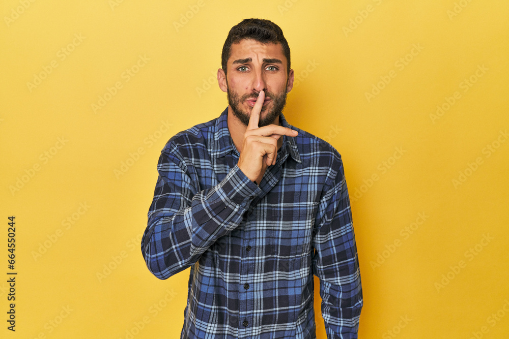 Young Hispanic man on yellow background keeping a secret or asking for silence. Young Hispanic man on yellow background keeping a secret or asking for silence.