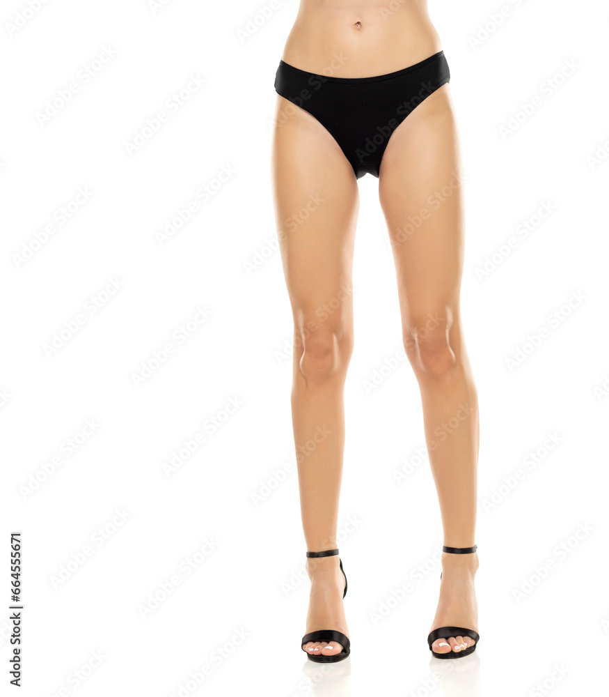 The elegance of women's legs is showcased as she stands confidently in high heels and black panties, exuding a sense of style and sophistication on a white background The elegance of women's legs is showcased as she stands confidently in high heels and black panties, exuding a sense of style and sophistication on a white background