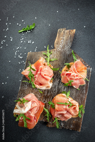 Open Sandwich with Prosciutto on a wooden board. vertical image. top view. place for text
