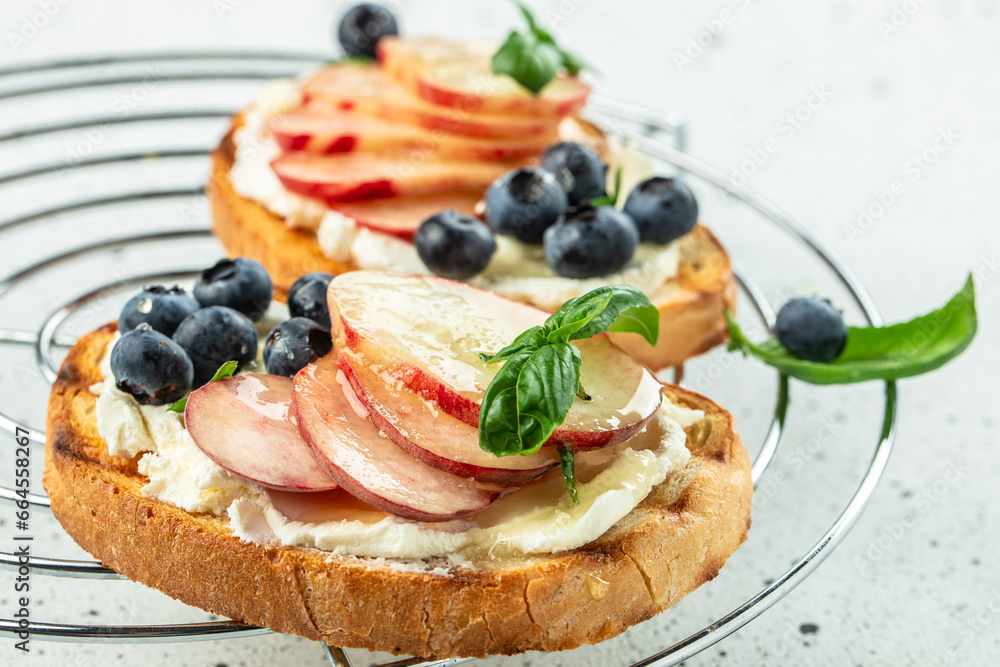 Peach bruschetta with ricotta cheese and blueberries on a wooden board. Food recipe background. Close up