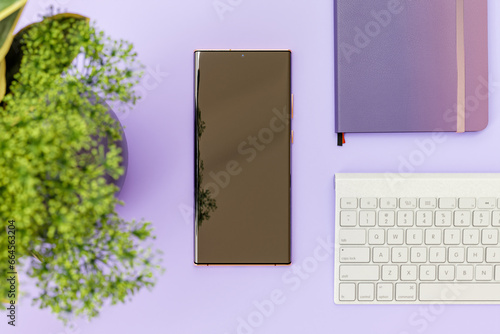 Smartphone On a working desk With green Table plant, Key broad and a Diary. 3d Render Background.