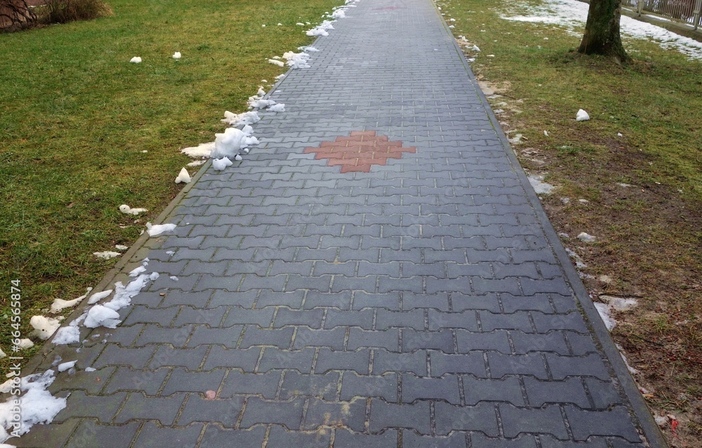 Thaw , approaching spring , small amount of snow snow on cobblestone pavement