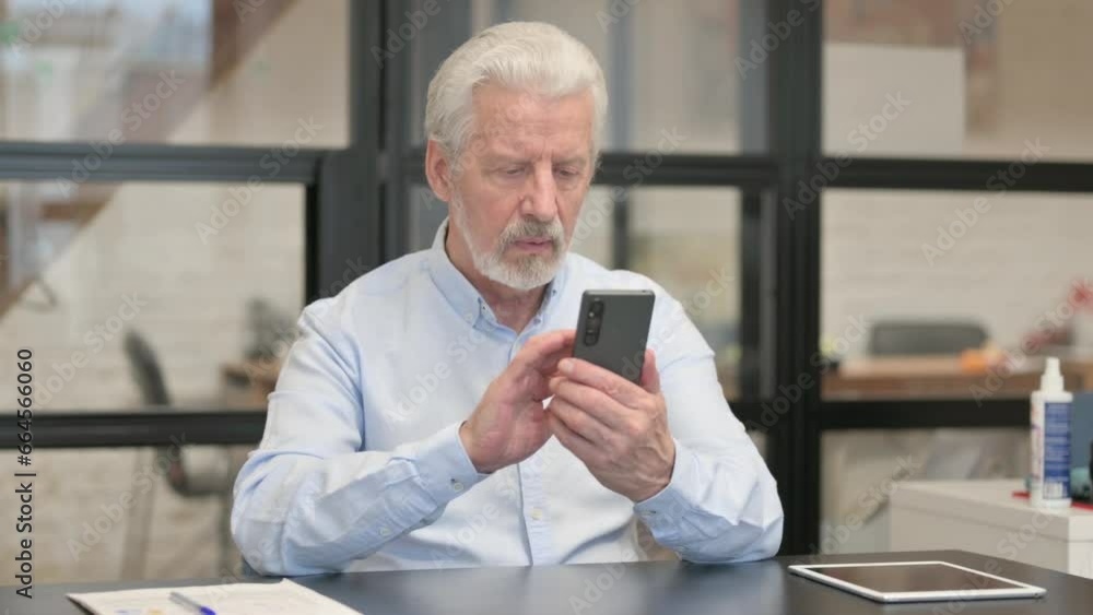 Old Businessman Browsing Internet on Phone in Office Old Businessman Browsing Internet on Phone in Office