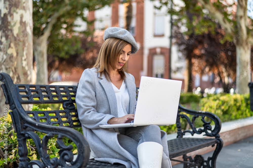 Young adult woman working with a laptop in a city park. Young adult woman working with a laptop in a city park.