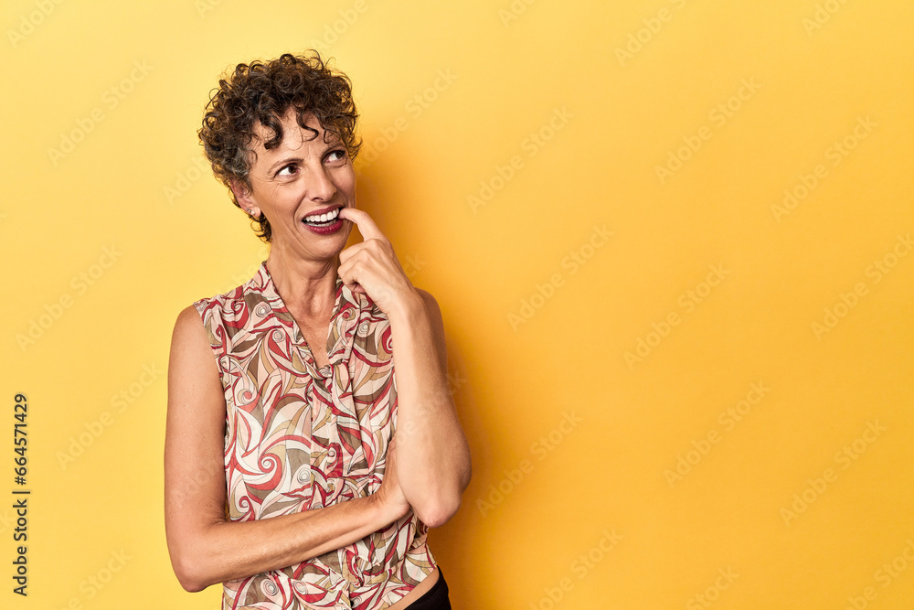 Mid-aged caucasian woman on vibrant yellow relaxed thinking about something looking at a copy space. Mid-aged caucasian woman on vibrant yellow relaxed thinking about something looking at a copy space.
