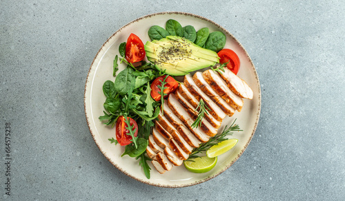 Fresh green salad with grilled chicken fillet, tomatoes, avocado, lemon on light background. Diet Concept. Top view copy space
