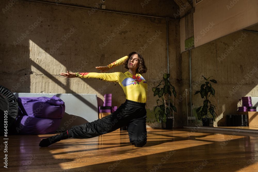 A girl dances a contemporary dance in a sunlit studio