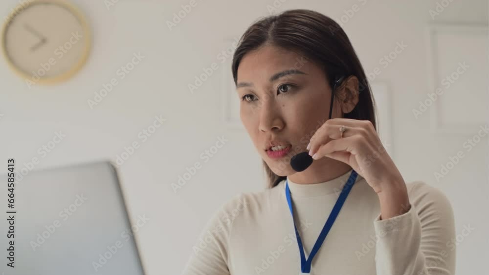 Tilt up shot of female entrepreneur talking with co-workers during video call on laptop using headset Tilt up shot of female entrepreneur talking with co-workers during video call on laptop using headset